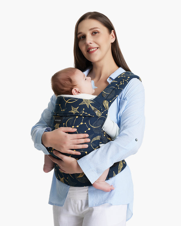 Mother wearing light blue shirt holding her baby in front-facing baby carrier with starry night pattern from Momcozy