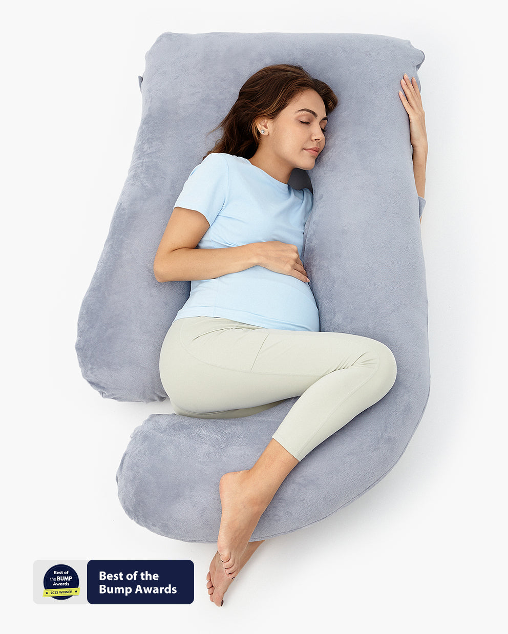 Pregnant woman comfortably resting on a U-shaped maternity body pillow, Best of the Bump Awards winner, gray plush support.